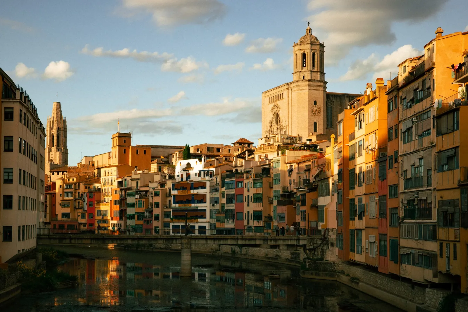Kleurrijke huizen en de kathedraal van Girona weerspiegeld in de rivier de Onyar, in avondlicht