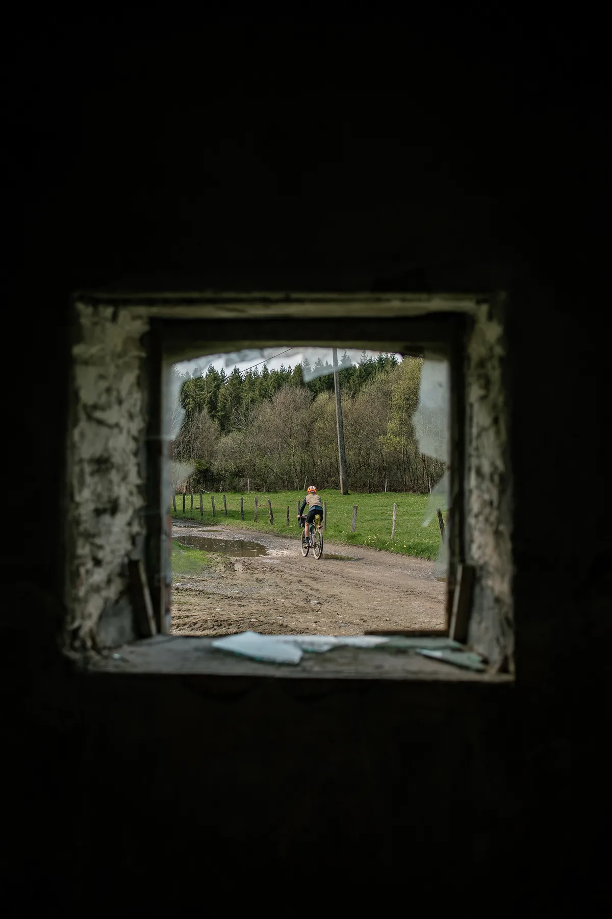 Uitzicht door de raamopening van een schuilhut op een fietser buiten
