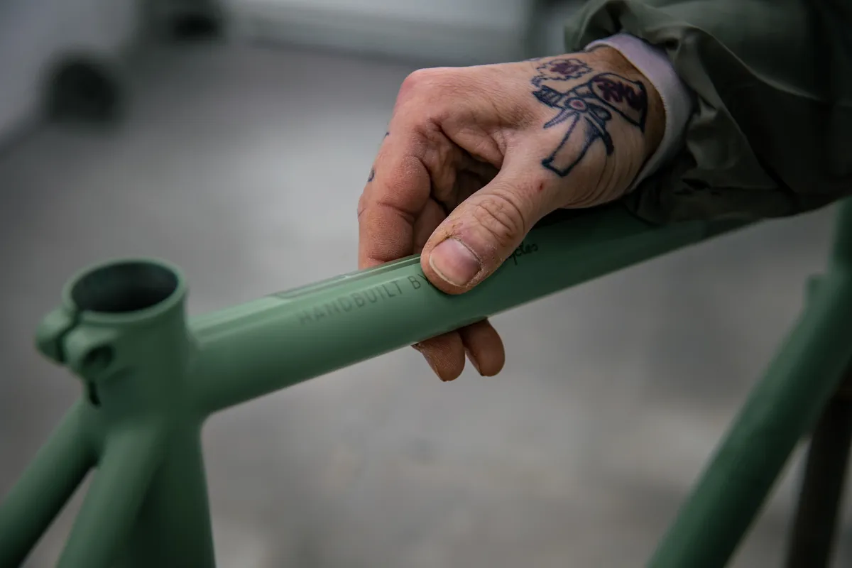 Hand met tatoeage op een pas gespoten groen frame, detail