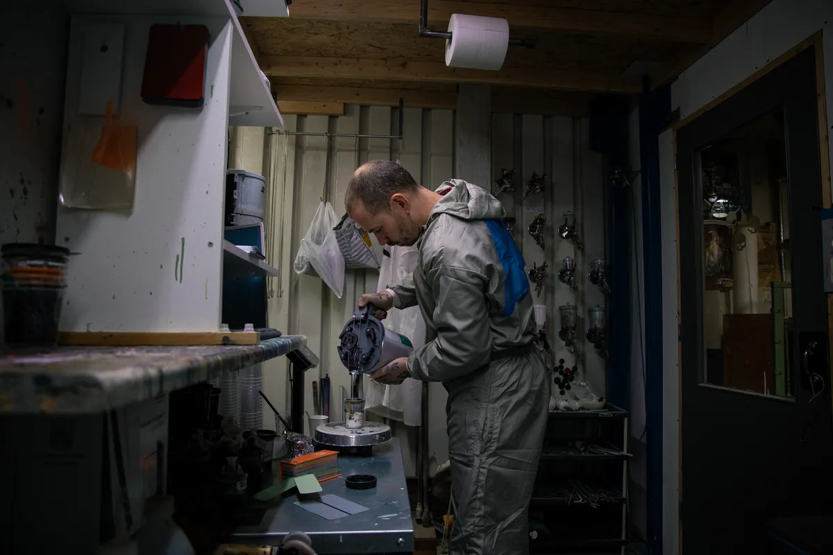 Framebouwer met stofmasker in de deuropening van de werkplaats