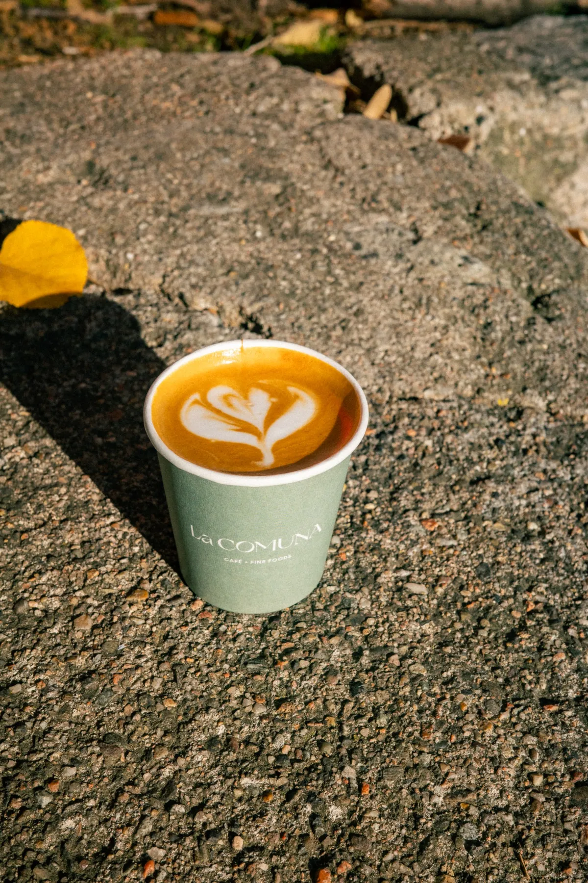 Beker koffie met latte art op een stenen muurtje