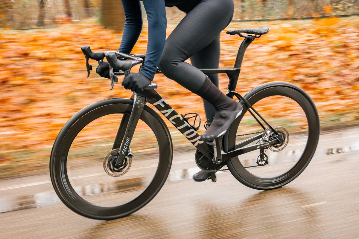 Wielrenner op een Factor-racefiets in beweging, herfstbladeren op de achtergrond