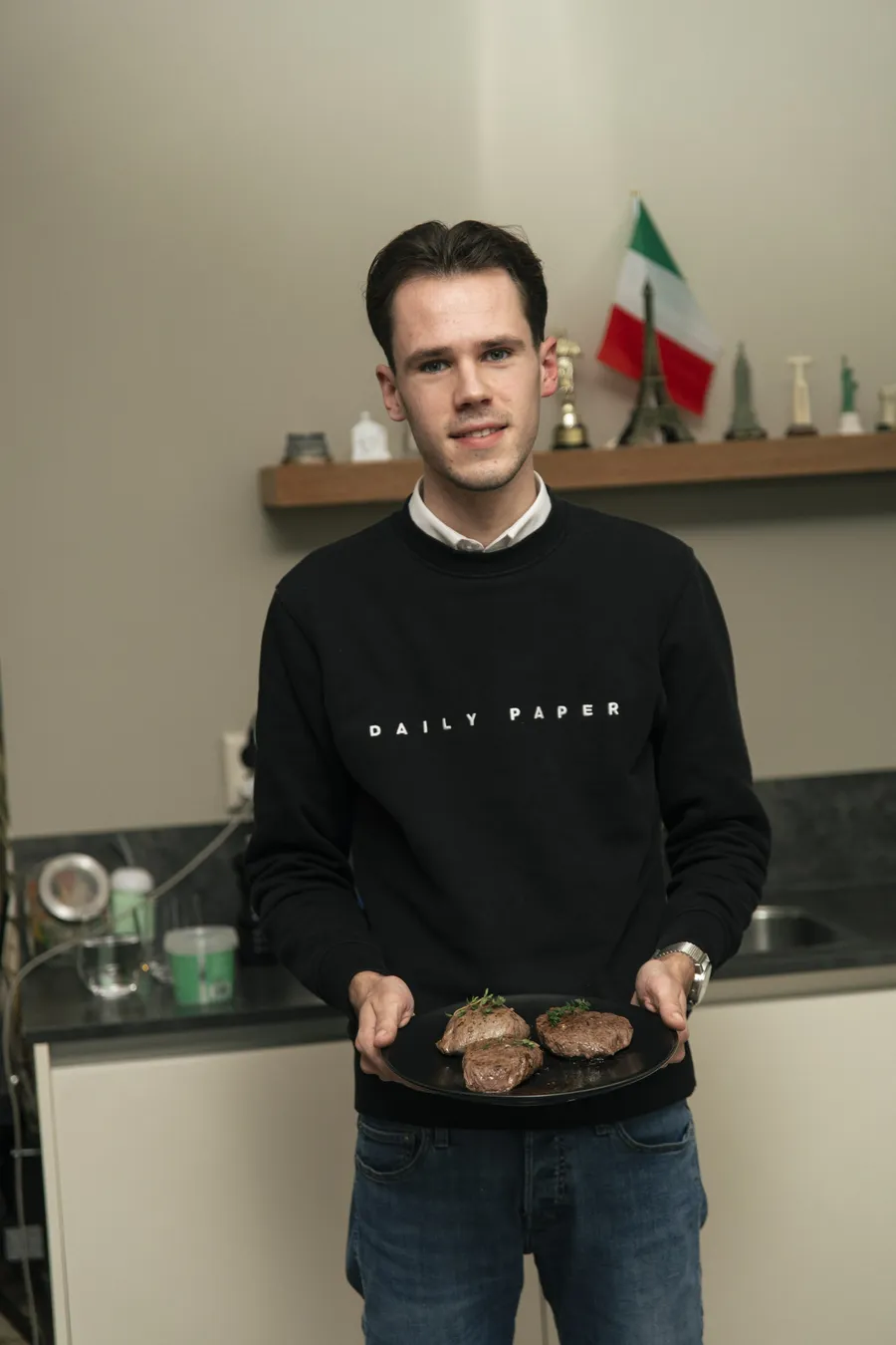 Portret van Jonathan de Koeijer in zijn keuken, met een bord in handen